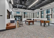 Thumbnail 27 of 39 - A room with a carpeted floor and a variety of seating options including a couch, chairs, and a table.