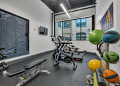 Thumbnail 25 of 39 - A gym with a rowing machine, dumbbells, and exercise balls.