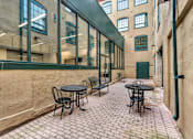 Thumbnail 24 of 39 - A patio with tables and chairs is surrounded by a wall.