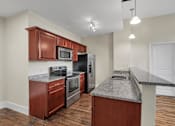 Thumbnail 6 of 39 - A kitchen with a granite countertop and wooden cabinets.