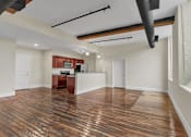 Thumbnail 11 of 39 - A room with wooden floors and a kitchenette in the corner.