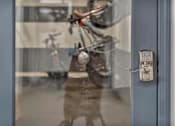 Thumbnail 39 of 39 - A person is standing in front of a glass door with a bicycle reflected in it.