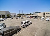 Thumbnail 15 of 25 - A parking lot with several cars and a building in the background.