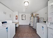 Thumbnail 13 of 25 - A laundry room with washing machines and a bench.