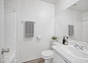 Thumbnail 5 of 25 - A white bathroom with a toilet, sink, and mirror.