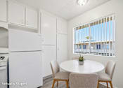 Thumbnail 3 of 25 - A kitchen with a table and chairs in front of a window.