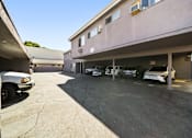 Thumbnail 6 of 7 - A parking lot with a building and cars.