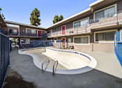 Thumbnail 7 of 7 - A skate park with a concrete bowl and a blue fence.