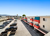 Thumbnail 17 of 17 - A parking lot with cars and a building with red and green stripes.