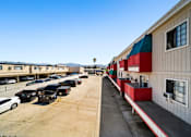 Thumbnail 13 of 17 - A parking lot with cars and a building with red and green awnings.