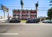Thumbnail 1 of 17 - A black car is parked on the left side of the street.