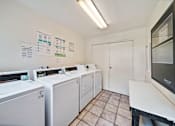 Thumbnail 16 of 17 - A laundry room with washers and dryers and a white door.