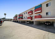 Thumbnail 11 of 17 - A parking lot in front of a building with a palm tree in the background.