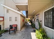 Thumbnail 10 of 17 - A long, narrow walkway between two buildings with benches on the left side.