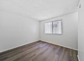 Thumbnail 22 of 25 - A room with wooden flooring and a window with blinds.