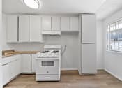 Thumbnail 17 of 25 - A white kitchen with a stove and cabinets.