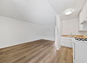 Thumbnail 19 of 25 - A kitchen with a white stove and wooden floors.