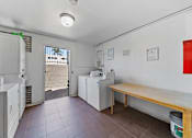 Thumbnail 14 of 25 - A kitchen area with a washing machine and a dining table.