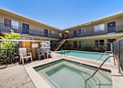Thumbnail 10 of 25 - A pool in a courtyard surrounded by chairs and a building.
