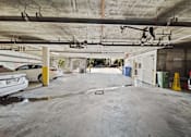 Thumbnail 5 of 6 - A parking garage with a white car parked on the left side.