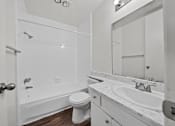 Thumbnail 11 of 19 - A white bathroom with a toilet, sink, and bathtub.