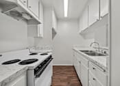 Thumbnail 10 of 19 - A kitchen with white appliances and cabinets.