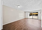 Thumbnail 9 of 19 - A  large room with wooden flooring and a sliding glass door.