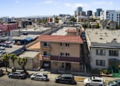 Thumbnail 1 of 10 - A parking lot with cars and buildings in the background.