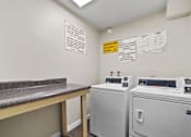 Thumbnail 3 of 10 - A laundry room with washers and dryers and a counter.
