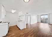 Thumbnail 18 of 27 - A white kitchen with wooden floors and a large window.