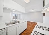 Thumbnail 23 of 27 - A modern kitchen with white cabinets and a wooden floor.