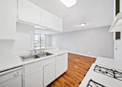 Thumbnail 22 of 27 - A kitchen with white cabinets and a white counter top.