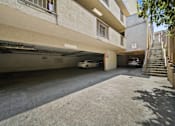 Thumbnail 4 of 9 - A car is parked in a garage under a building with a staircase on the right side.