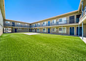 Thumbnail 1 of 10 - A sunny day at the courtyard of a building with blue doors and windows.