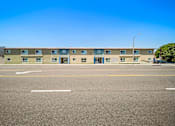 Thumbnail 4 of 10 - A row of apartment buildings with a clear blue sky above.