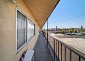 Thumbnail 11 of 17 - A balcony with a bench and a window overlooking a parking lot.