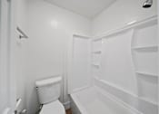 Thumbnail 17 of 17 - A white toilet sits next to a white bathtub in a small bathroom.