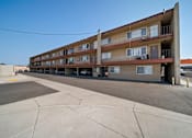 Thumbnail 1 of 17 - A large apartment complex with a parking lot in front.