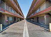 Thumbnail 2 of 17 - A long, narrow road separates two rows of apartment buildings.