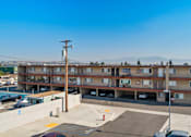 Thumbnail 3 of 17 - A parking lot in front of a multi-story apartment building.