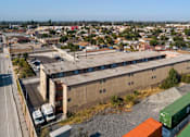 Thumbnail 5 of 17 - A train with green and orange containers is passing by a large building.