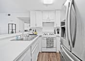 Thumbnail 8 of 12 - A modern kitchen with white appliances and cabinets.