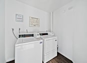 Thumbnail 10 of 12 - A white wall with a washing machine and dryer in front of it.