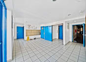 Thumbnail 11 of 12 - A hallway with blue doors and white walls.