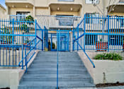 Thumbnail 3 of 12 - A blue gate leads to a building entrance.