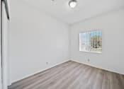 Thumbnail 10 of 12 - A room with a window covered by blinds and a wooden floor.