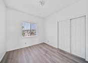 Thumbnail 8 of 12 - A room with a white door and a window with a view of a city.