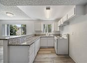 Thumbnail 12 of 15 - A kitchen with white cabinets and a granite countertop.