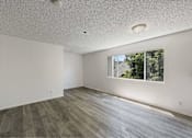 Thumbnail 3 of 15 - A room with a window and wooden flooring.
