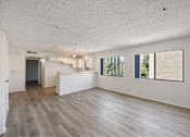 Thumbnail 6 of 15 - A spacious room with wooden flooring and a large window.